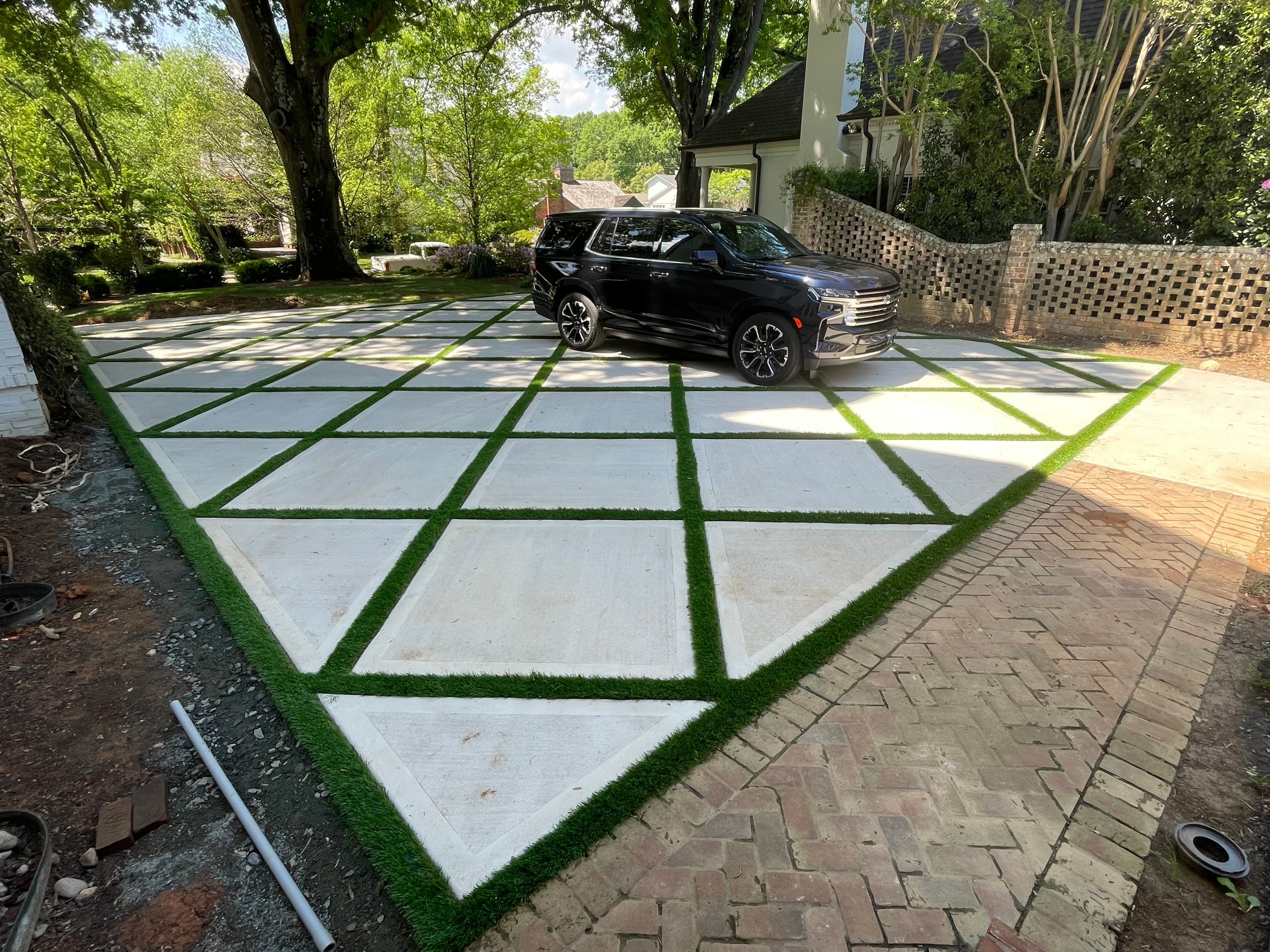Precision turf strips integrated into a modern concrete driveway.